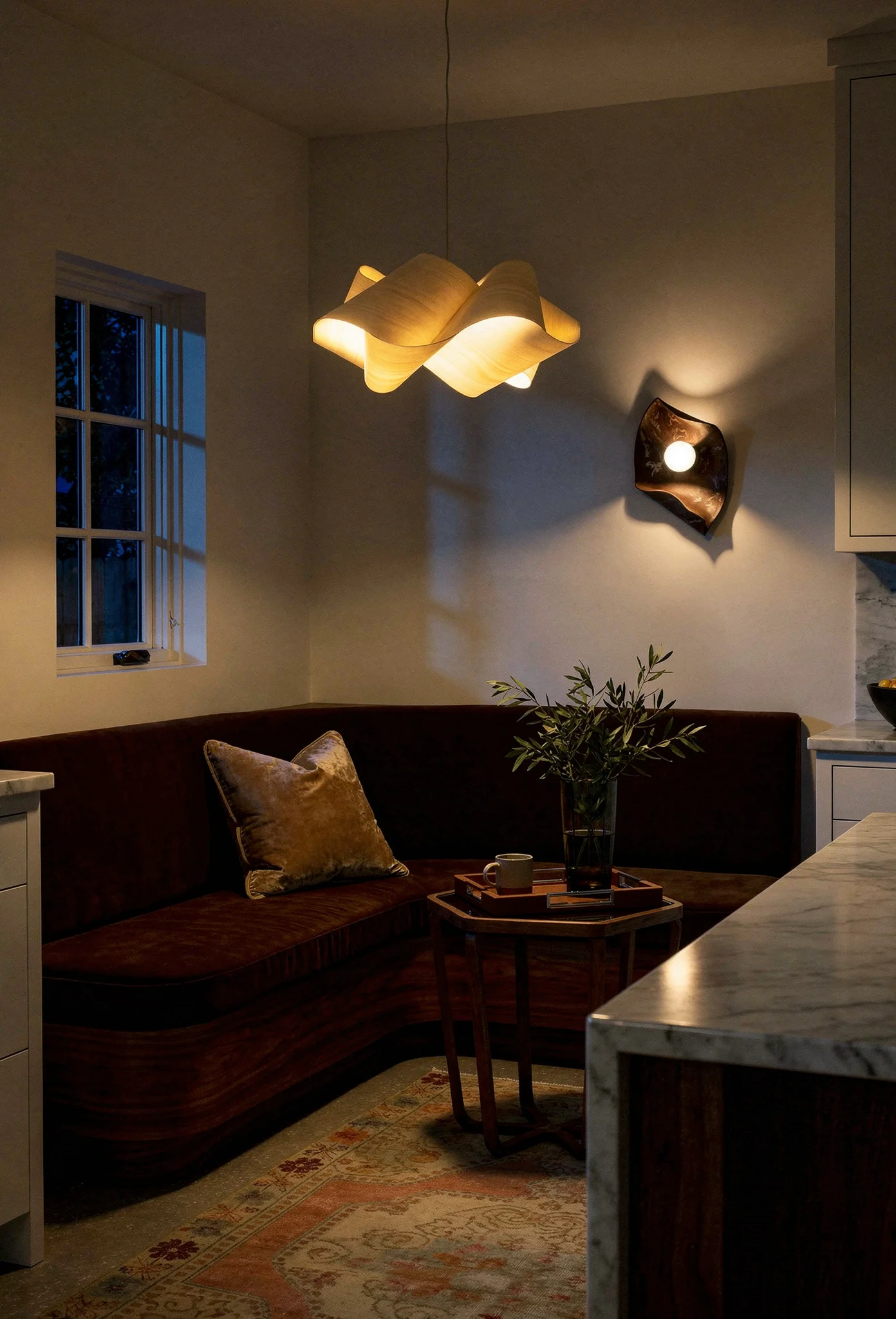 Modern kitchen banquette nook evening lighting featuring walnut side table with sculptural swirl pendant