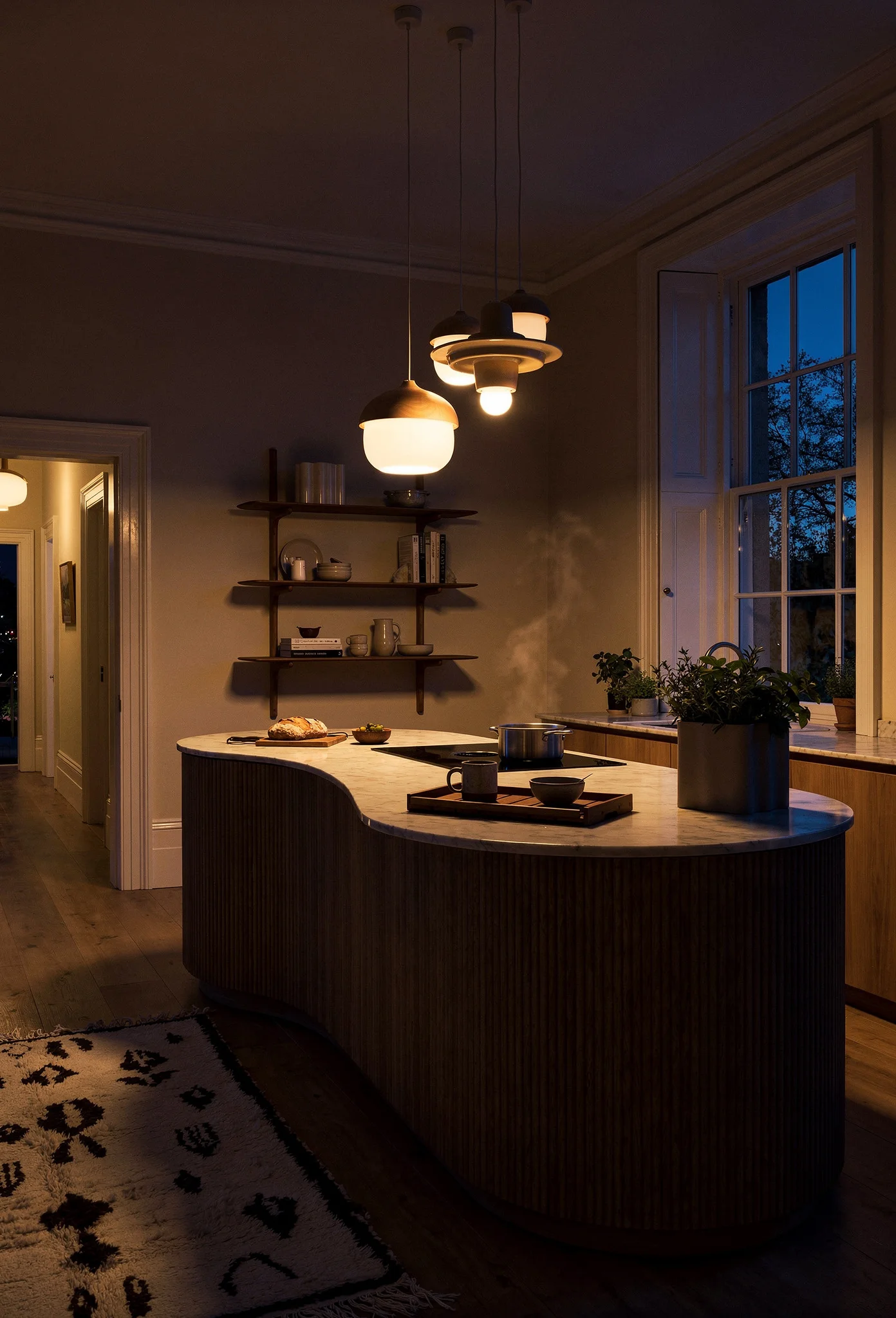 Modern kitchen evening lighting featuring ivory organic wood pendant with curved oak island